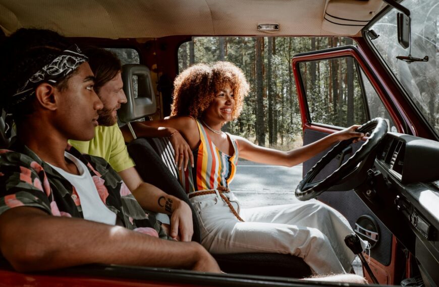 Young friends on a joyful summer road trip in a vintage car through the woods.