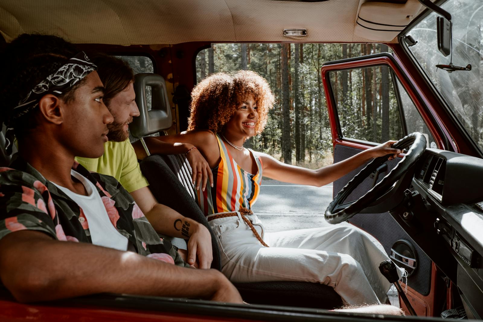 Young friends on a joyful summer road trip in a vintage car through the woods.