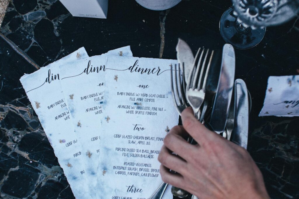 Close-up of an elegant dinner menu with cutlery on a black marble table.