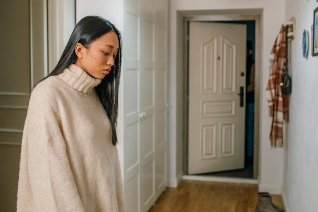 Pensive woman in a turtleneck sweater looking down indoors.