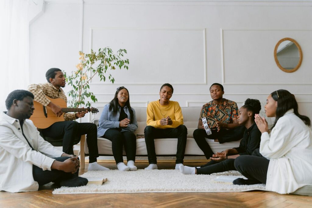 A diverse group of friends praying and singing together in a cozy living room setting.