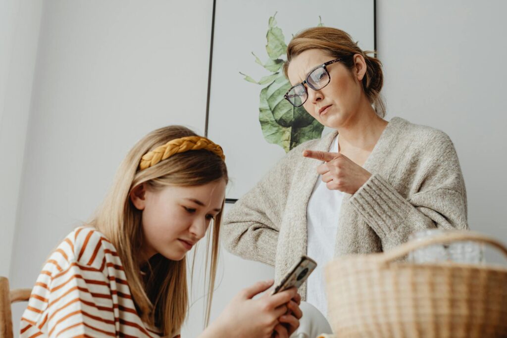 A mother scolds her teenage daughter for excessive phone use at home.