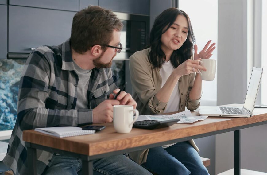 A couple having a discussion with coffee and laptops, reflecting relationship communication indoors.