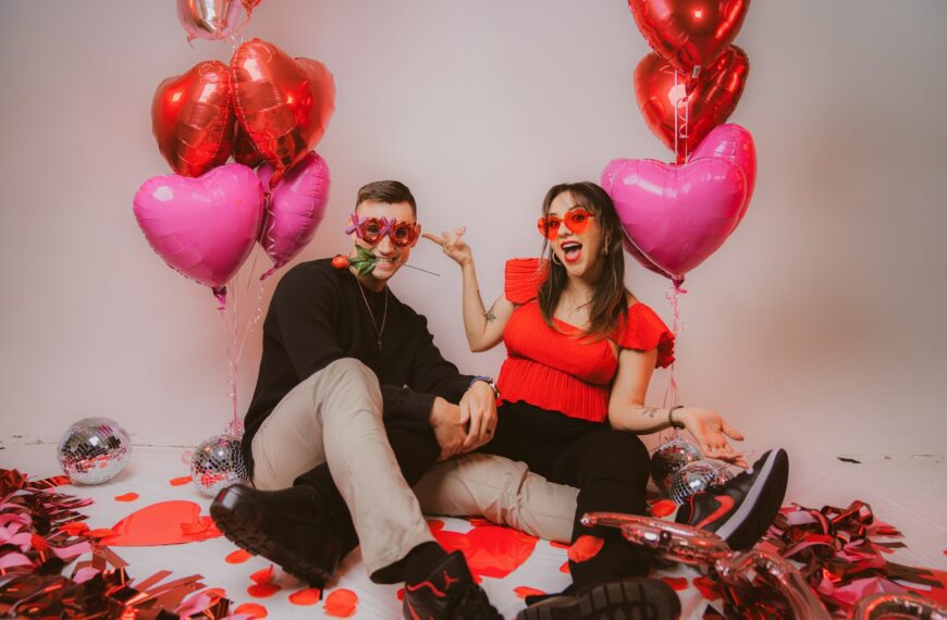 a man and a woman sitting on a floor with balloons and confetti