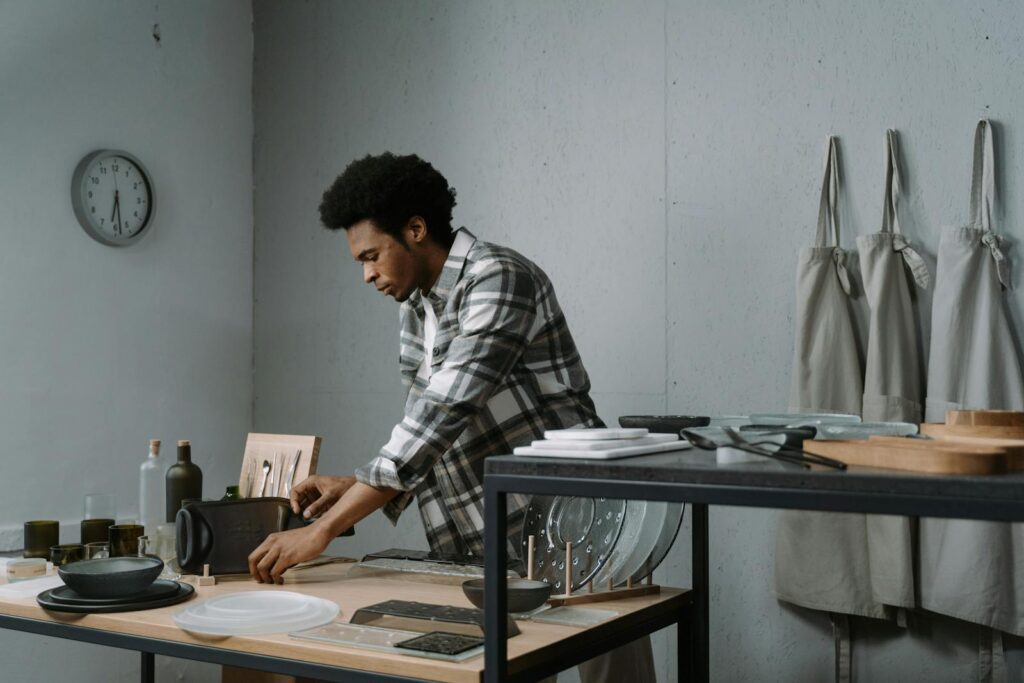 A man arranging kitchenware on a table in a modern indoor kitchen setting.