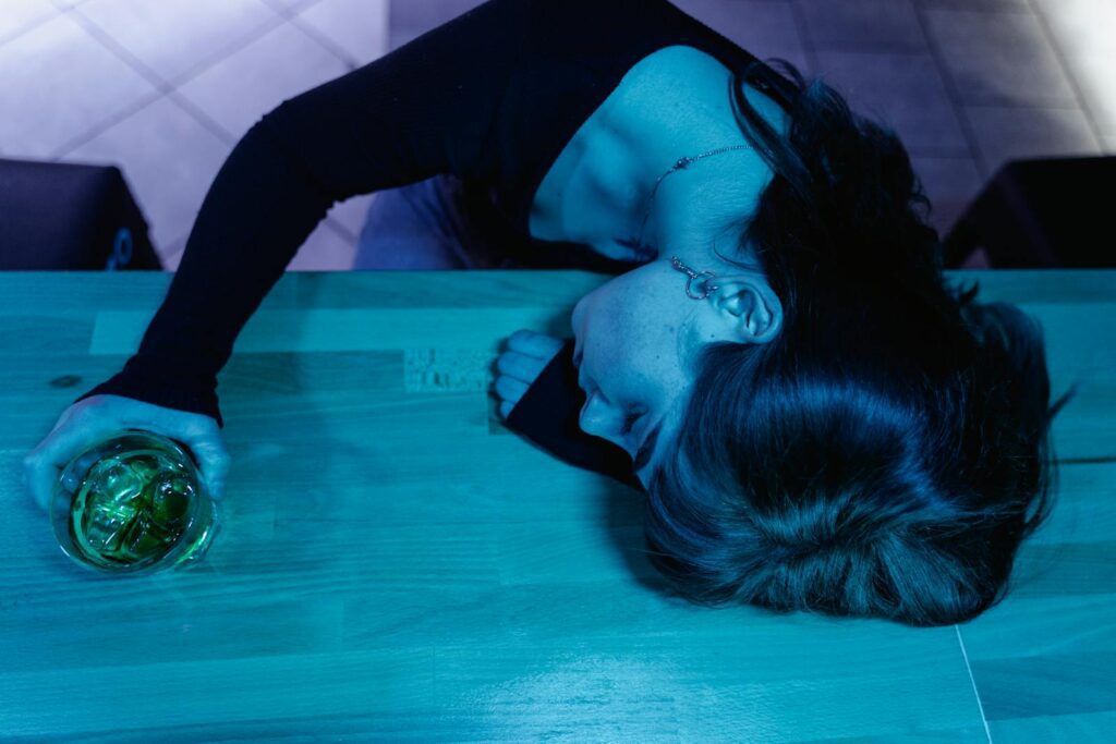 A woman with a drink sleeps on a bar counter, shot from above.