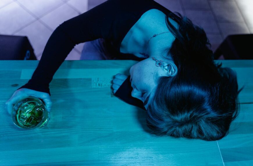 A woman with a drink sleeps on a bar counter, shot from above.