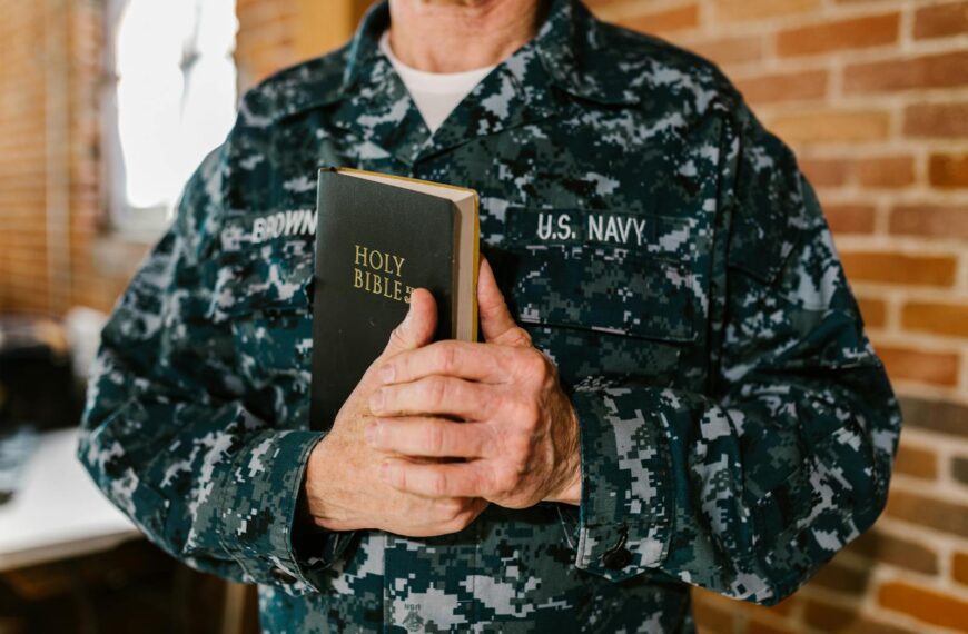 A U.S. Navy sailor in uniform holding a Holy Bible, symbolizing faith and service.