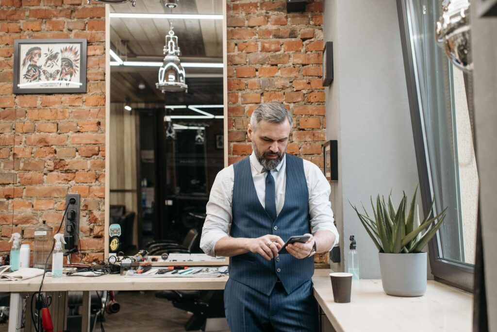 Businessman in a stylish barber shop checking phone. Modern and classic decor.