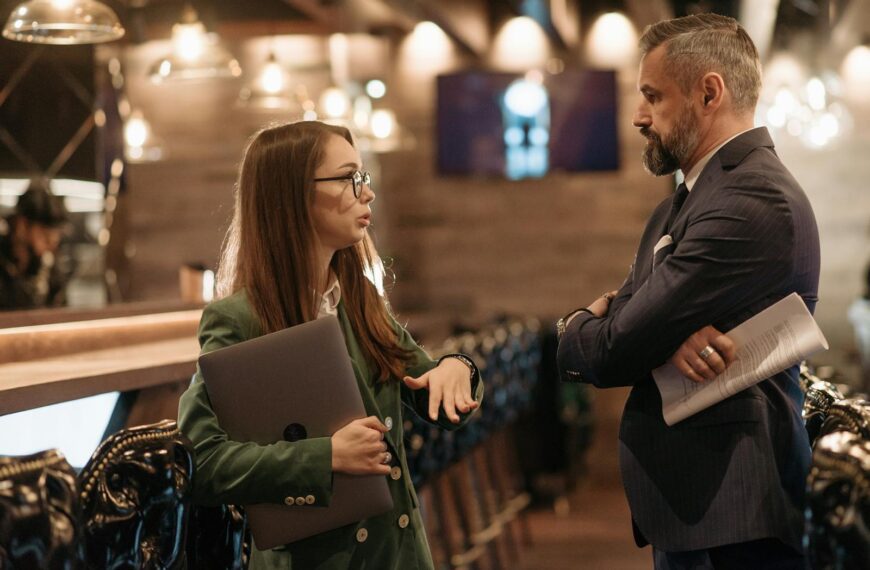 Two business professionals engaging in conversation in a stylish bar interior, highlighting modern work culture.