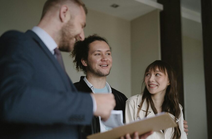 Happy young couple conversing with a realtor indoors about a new apartment.