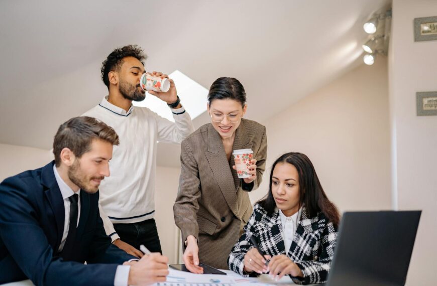 A diverse group of colleagues engaging in teamwork around a table in a modern office environment.