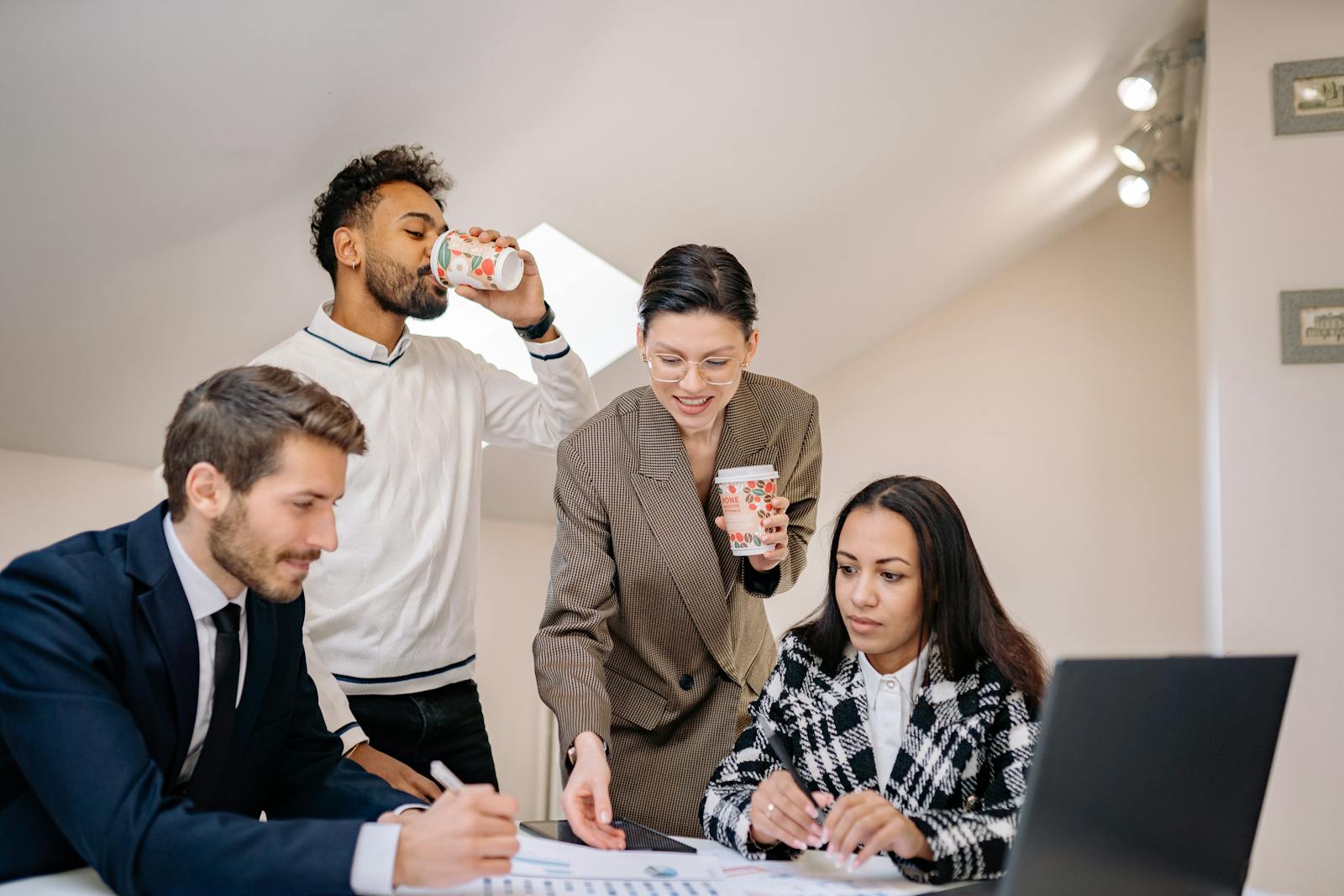 A diverse group of colleagues engaging in teamwork around a table in a modern office environment.