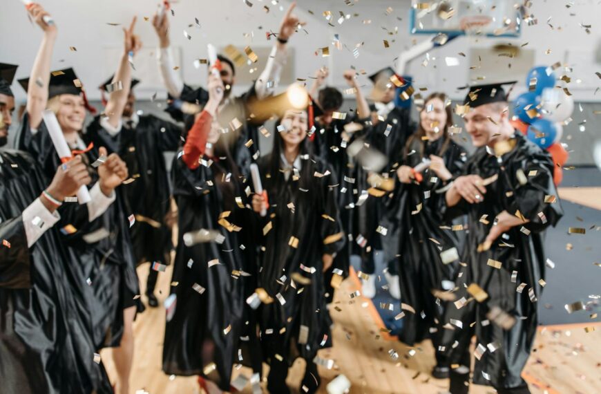 Excited graduates toss confetti in celebration, marking a special achievement moment indoors.