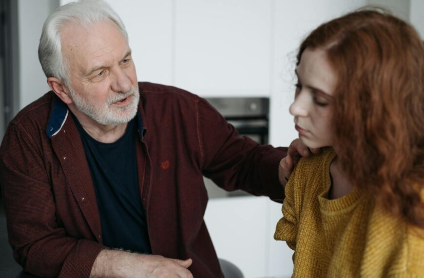 An elderly man consoles a young woman indoors, expressing empathy and understanding.