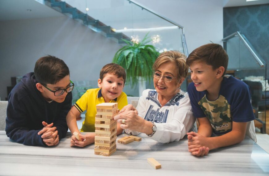 A joyful family moment with grandma and grandsons playing Jenga indoors, capturing quality time together.