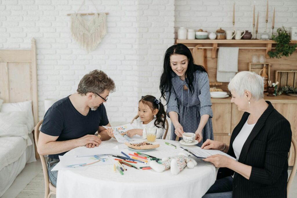 A joyful family with an adopted girl sitting and interacting at a table in a cozy home setting.