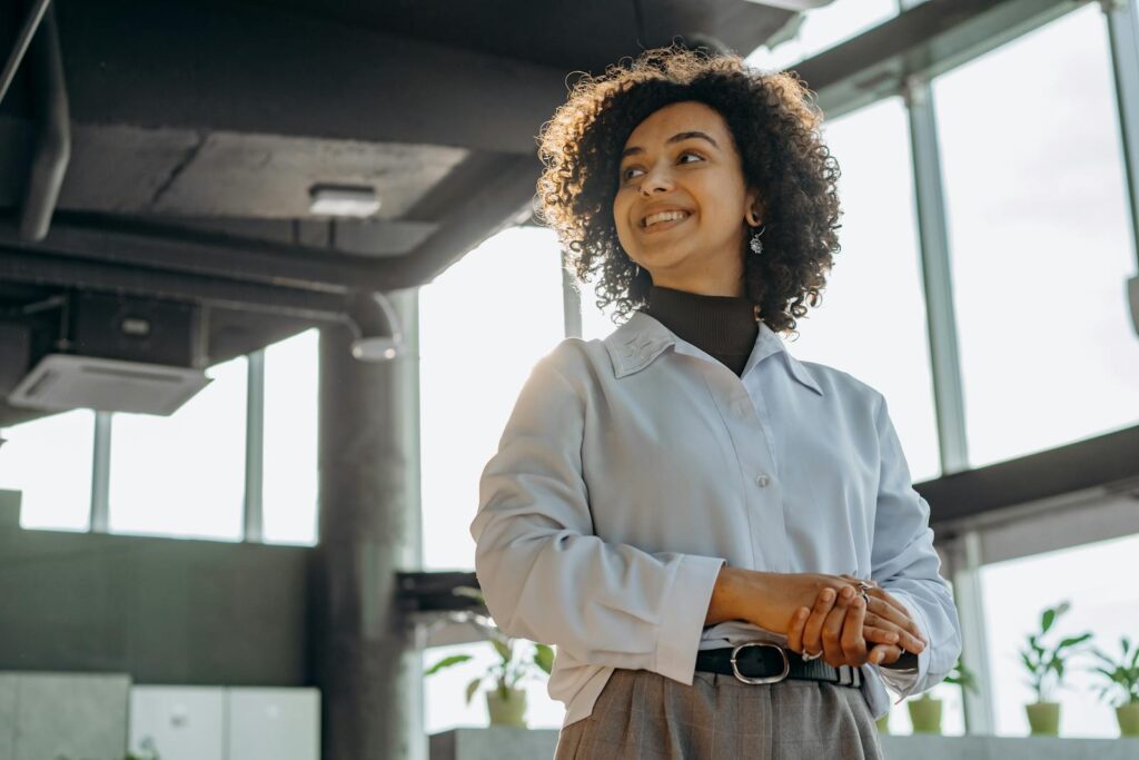 Confident businesswoman with curly hair in a bright, modern office environment.