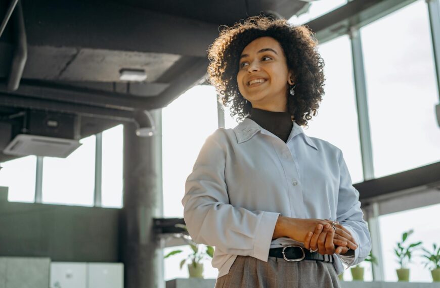 Confident businesswoman with curly hair in a bright, modern office environment.