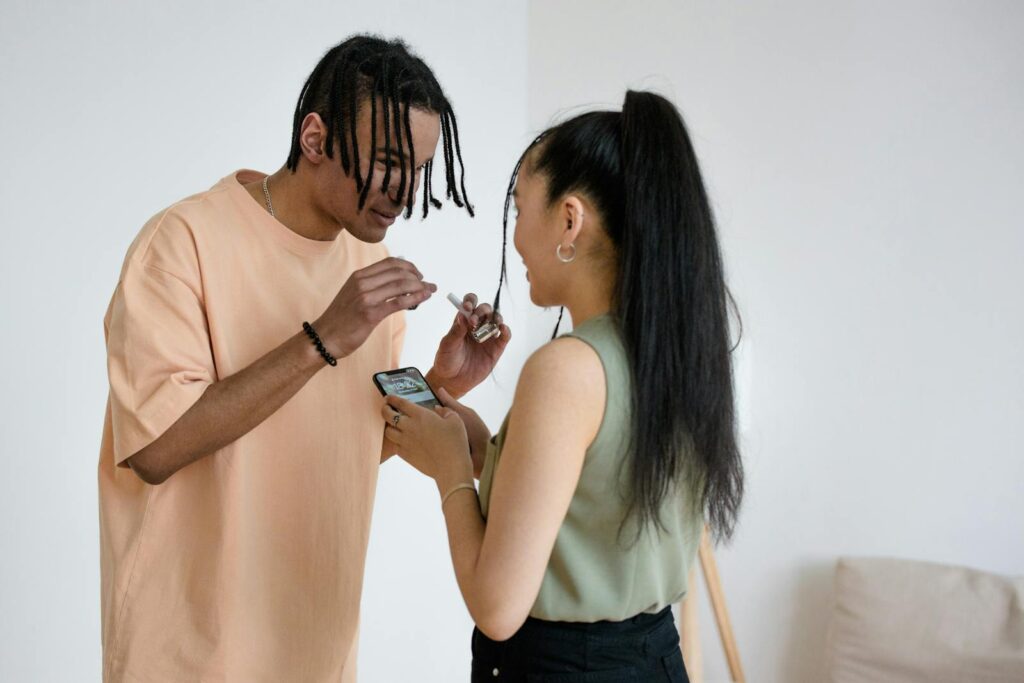 A man and woman engaging with a smartphone, smiling in a casual indoor setting.