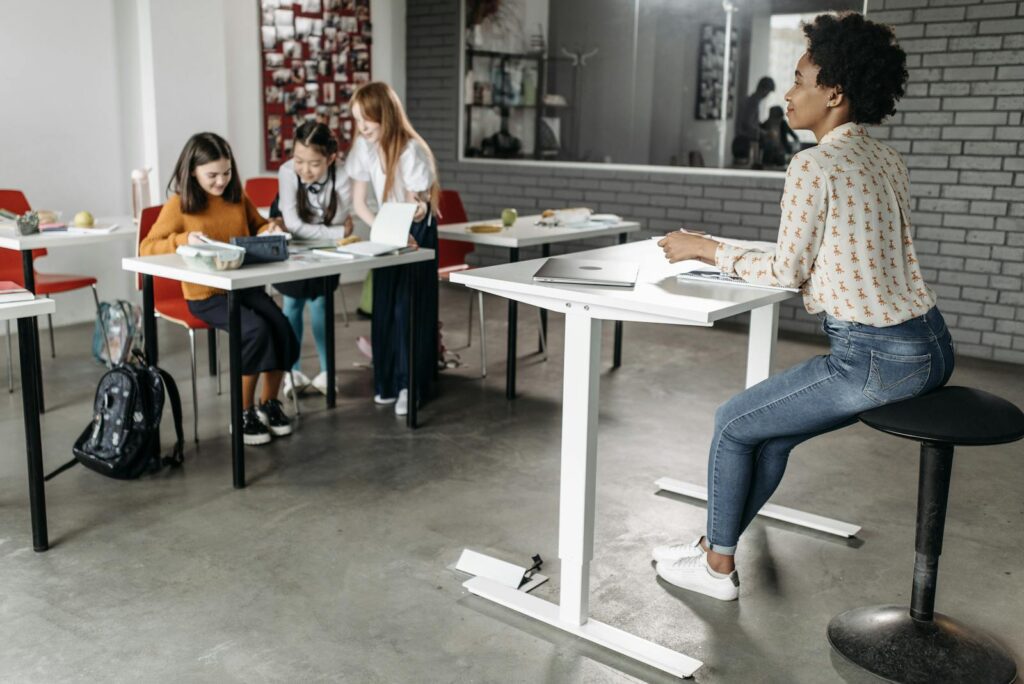 A diverse group of students engage in classroom learning with a teacher present to guide their studies.