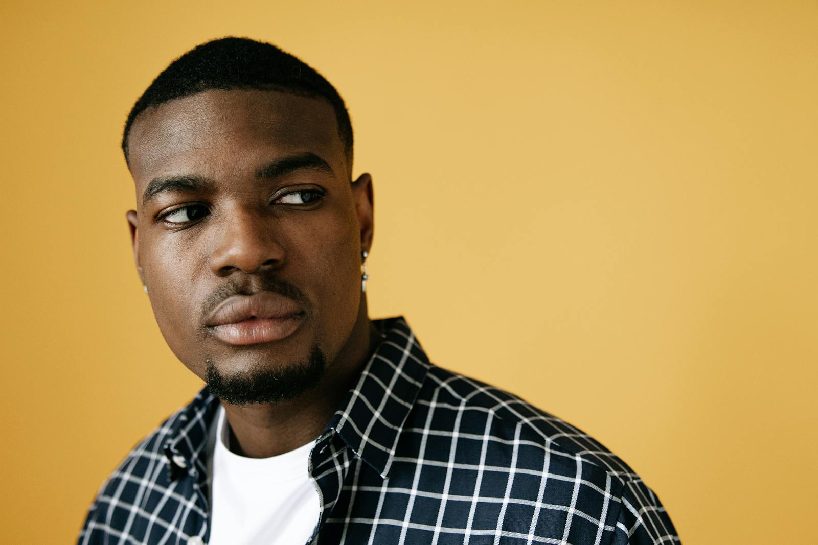 Studio portrait of an adult male with a thoughtful expression on a yellow background.