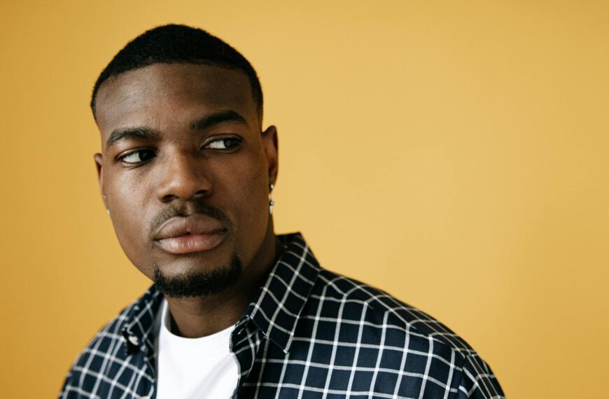 Studio portrait of an adult male with a thoughtful expression on a yellow background.