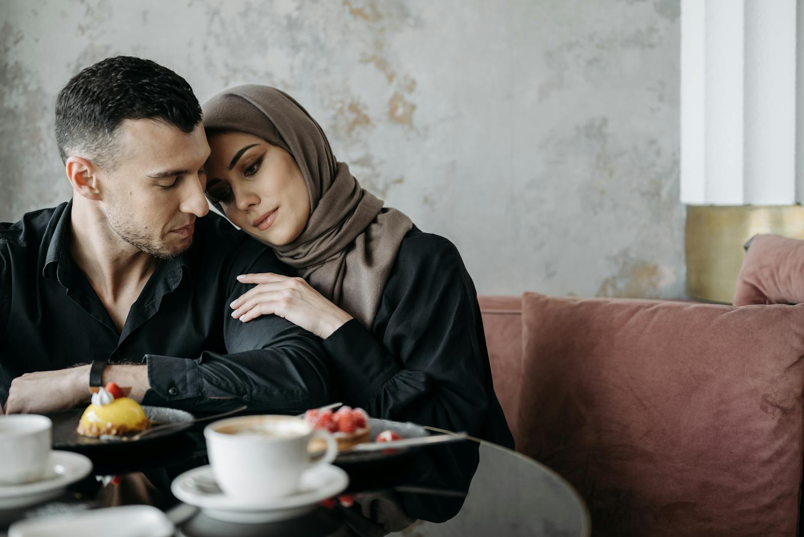 A loving Muslim couple sitting together in a cozy café setting, enjoying a serene moment.