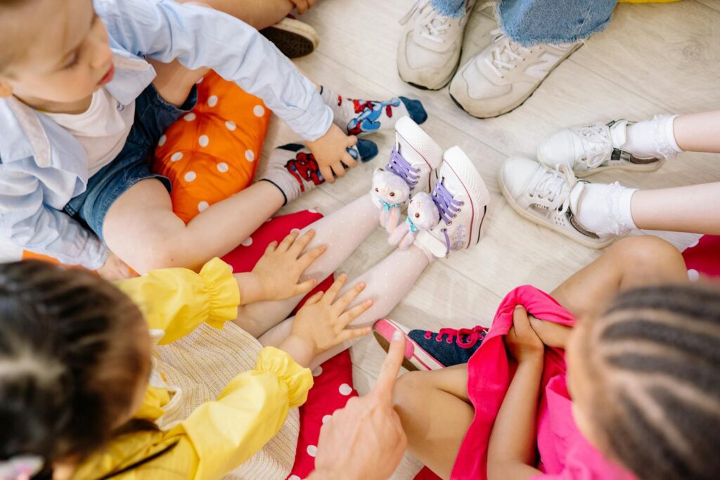 Children sitting in a circle on a wooden floor, engaging in fun indoor activities.