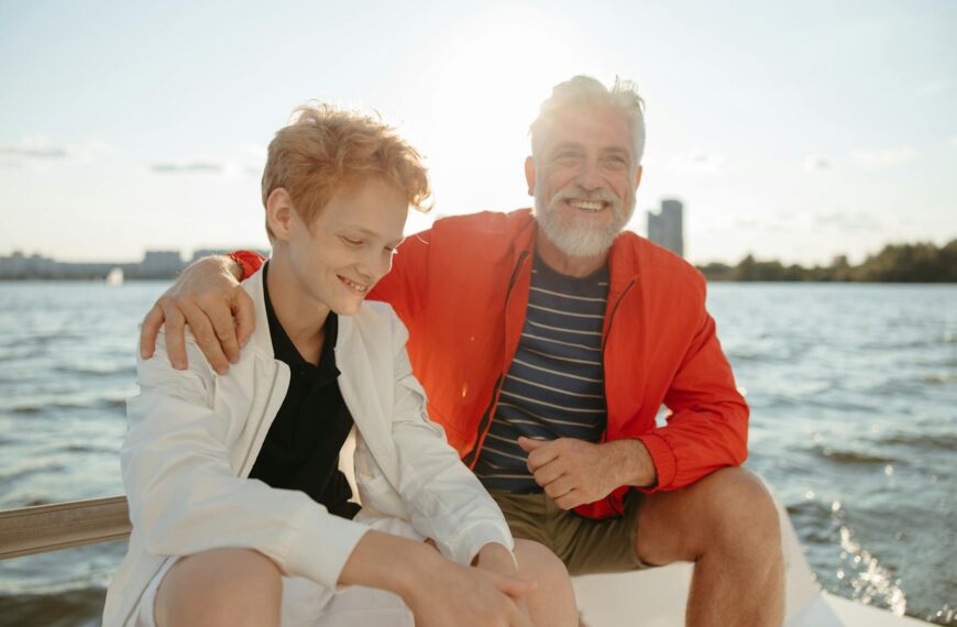 Smiling grandfather and grandson enjoy a sunny day on a boat, creating cherished memories.