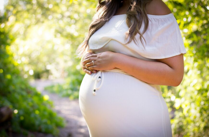 pregnant woman standing near green plants