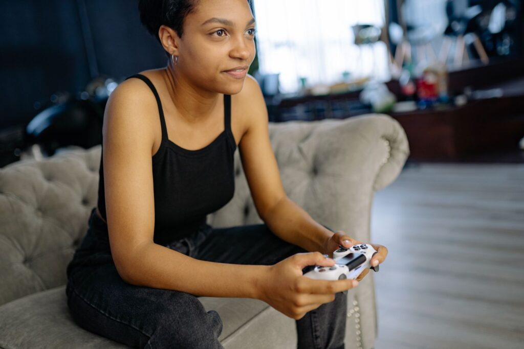 Woman enjoying leisure time playing video games at home on a cozy sofa.