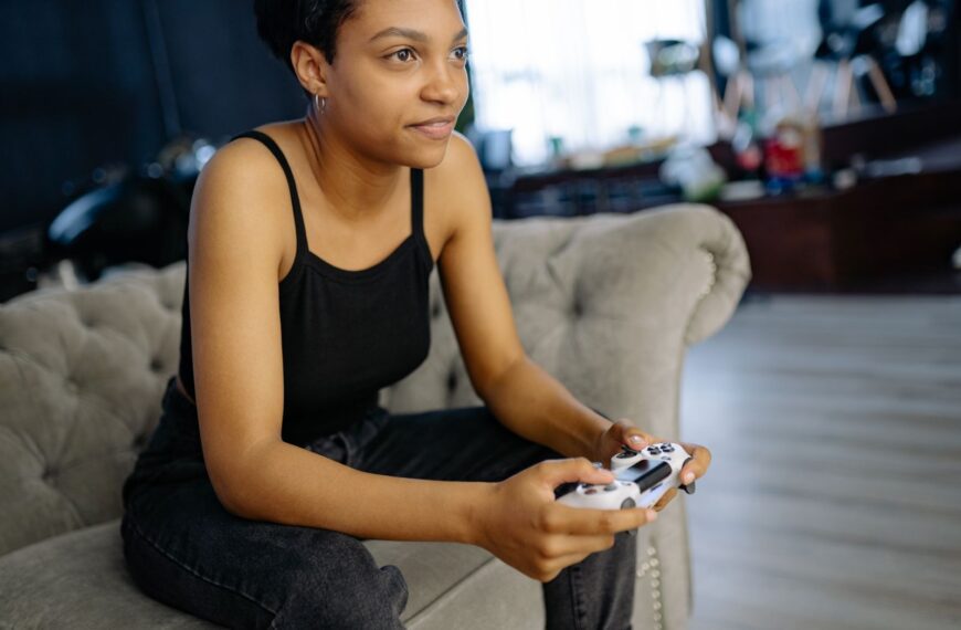 Woman enjoying leisure time playing video games at home on a cozy sofa.