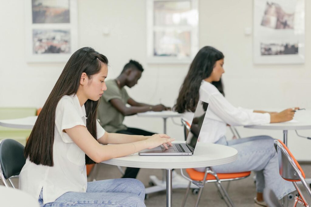 Students focused on learning in a contemporary university setting with laptops and notebooks.