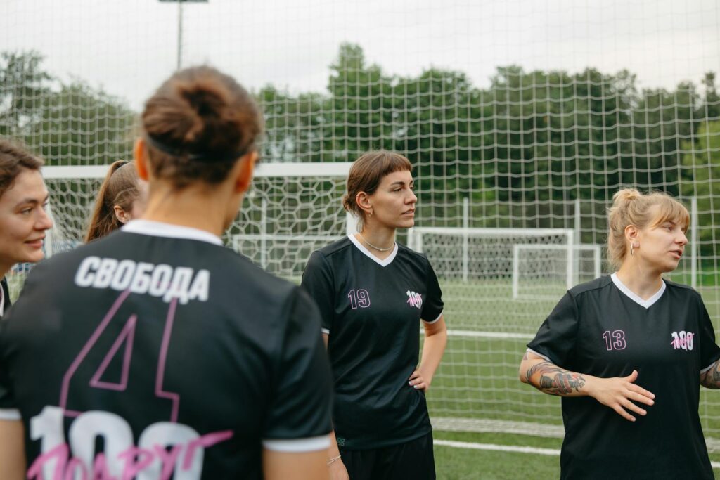 Female soccer players discussing strategy on an outdoor field.