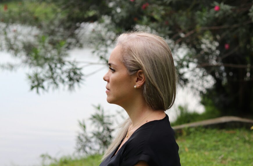 a woman with blonde hair standing in front of a body of water