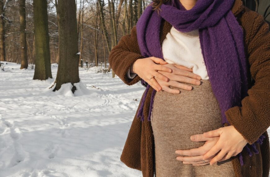 a woman standing in the snow holding her stomach