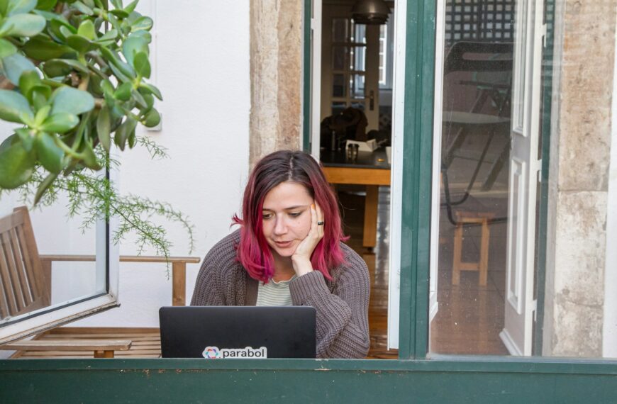 a woman with pink hair is looking at a laptop
