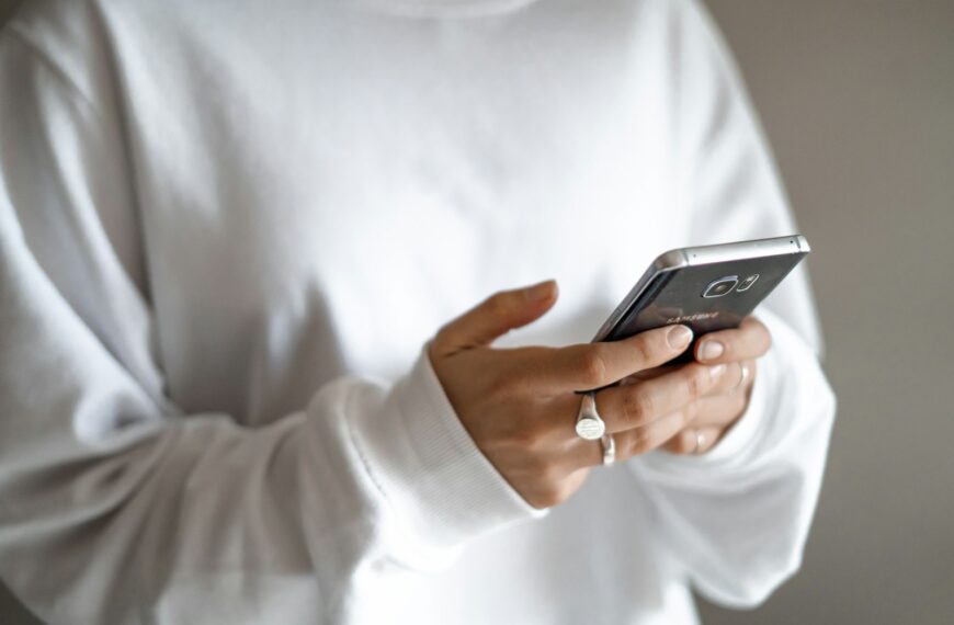 person in white long sleeve shirt holding black smartphone