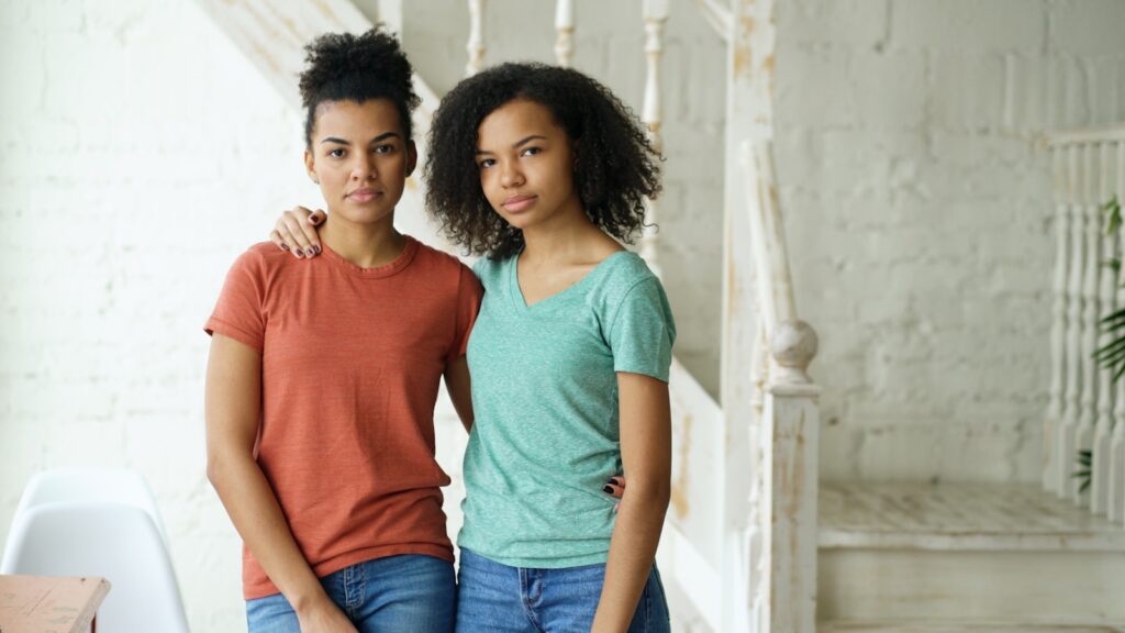 Two young women standing together indoors.