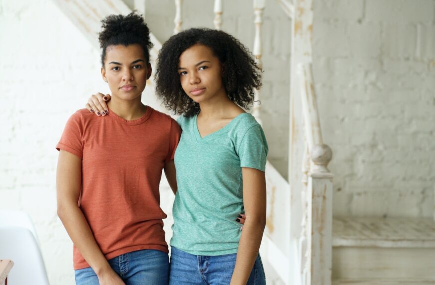 Two young women standing together indoors.