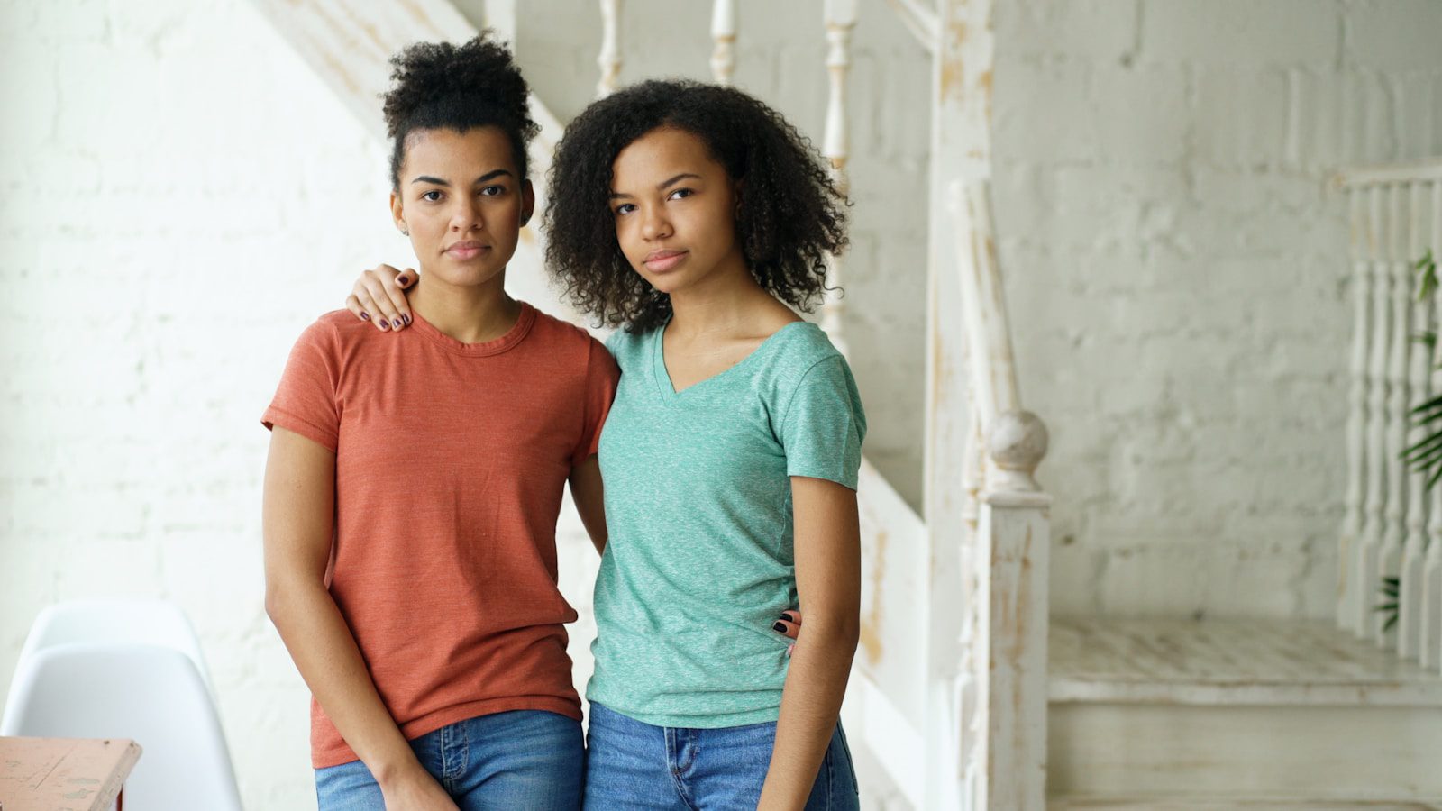 Two young women standing together indoors.