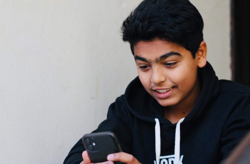 man in black and white hoodie holding black smartphone