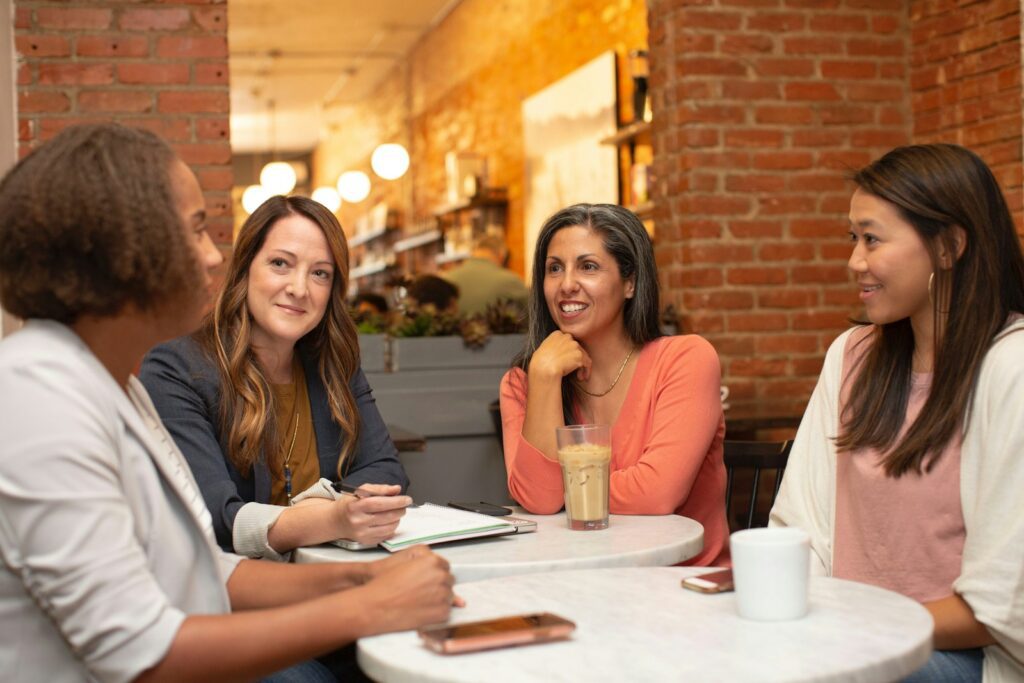 four women chatting at cafe table