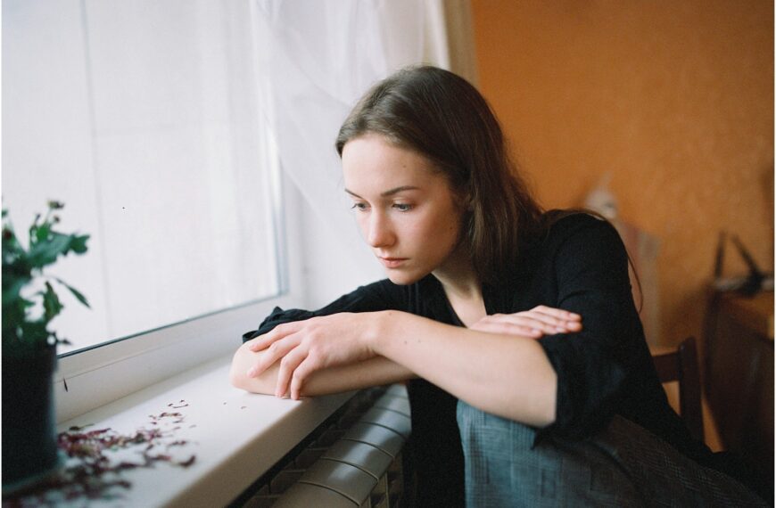 a woman sitting on a window sill looking out the window