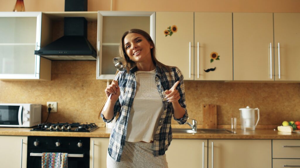 A woman dances in a bright, modern kitchen.