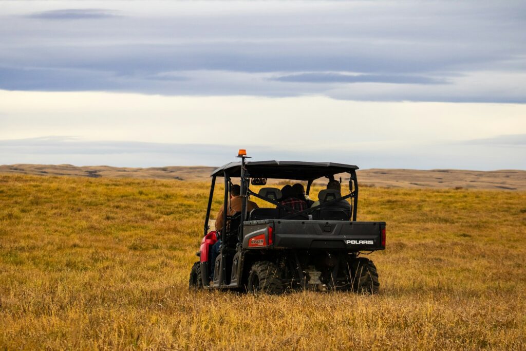 A red utility vehicle drives through a dry grassy field.