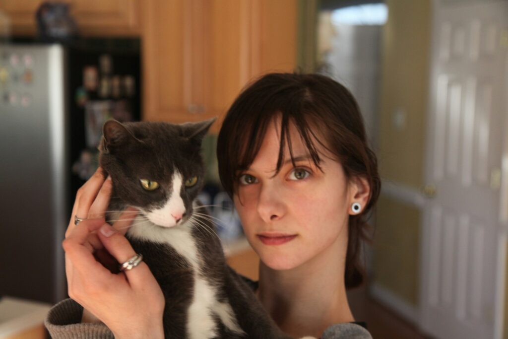 woman holding black and white cat