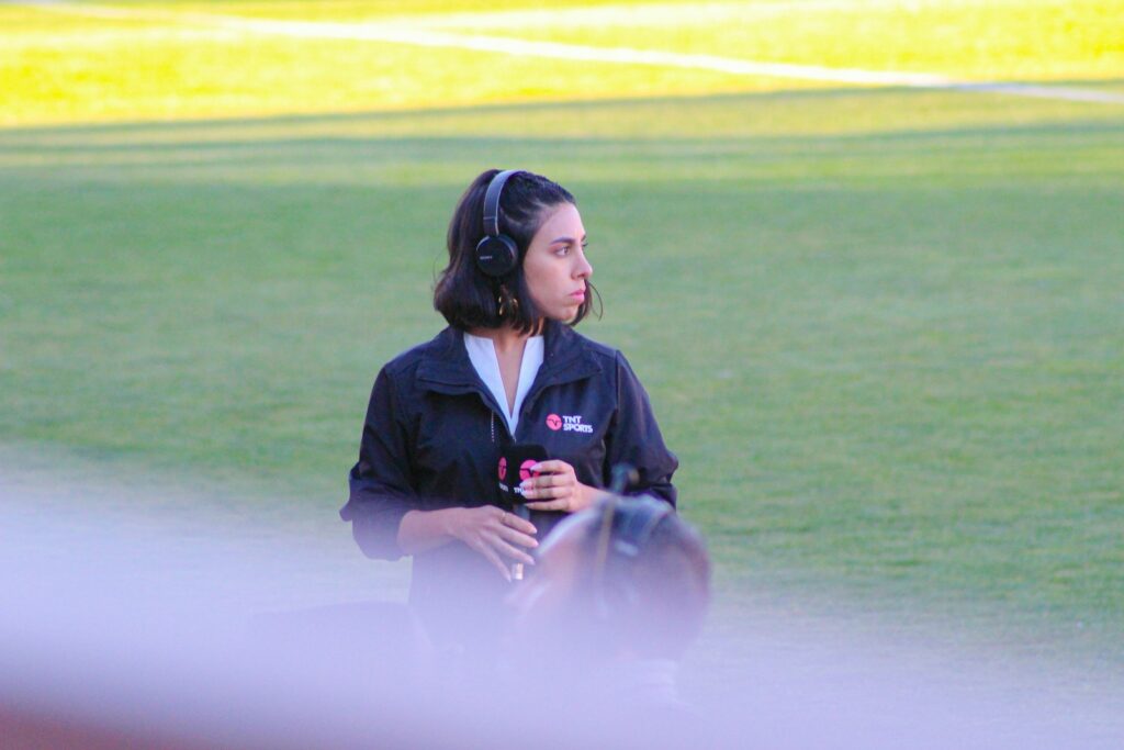 a woman with headphones standing on a baseball field