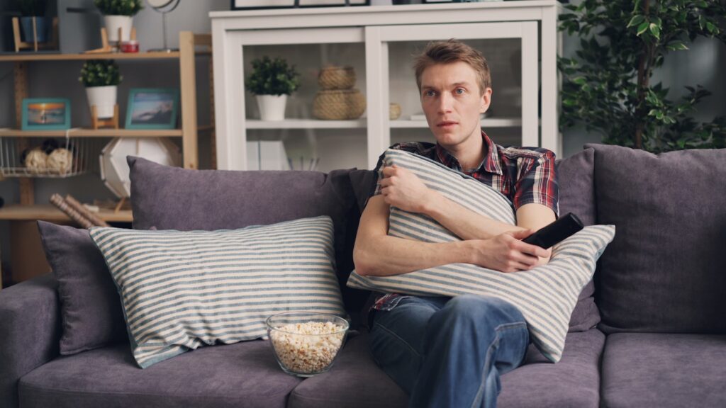 a man sitting on a couch holding a pillow